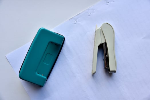 A white stapler and a green hole punch on a white background. Stationery on a white background. photo