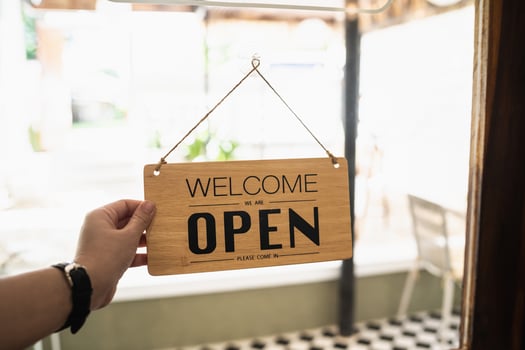 Hand woman hold open sign broad through the door glass. OPEN sign board through the glass of store window. text wooden board  door vintage shop sign opened store. photo