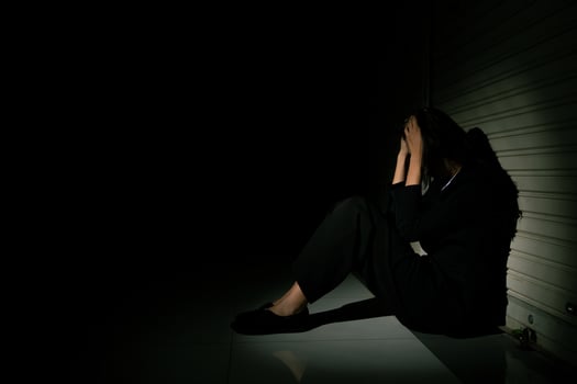 Woman depressed from sad stress pain despair problem, person sit on closed shop on corridor alone with emotion lonely desperate upset head down. Head in hand no way out concept, copy space photo