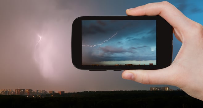 tourist photographs of lightning bolt over city photo