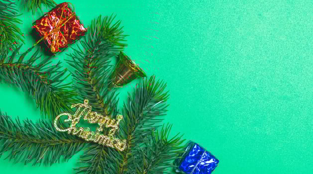 Top view of Christmas gift box red balls with spruce branches and bell on green background. photo