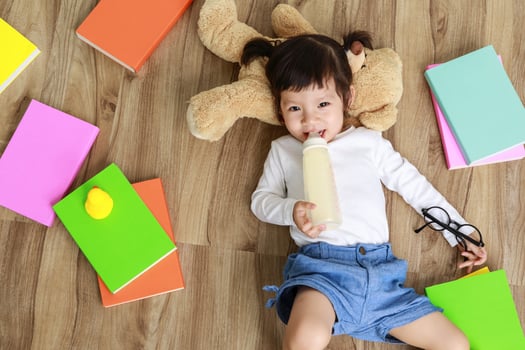 Little cute asian girl eating milk from bottle and nipple photo