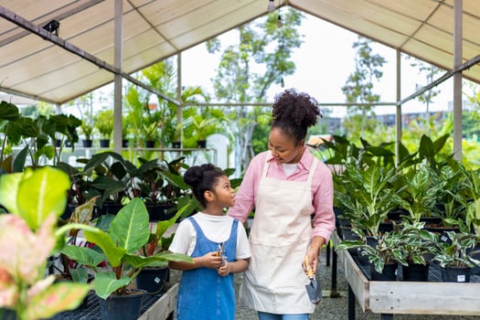 African mother is teaching her daughter to grow ornamental houseplant in their own nursery garden center full of exotic and tropical plant photo