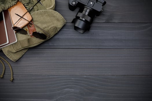 Top view mockup of Traveler's accessories with passport, books of travel plan, wallet, camera and backpack on black wooden desk empty space, Travel concept background photo