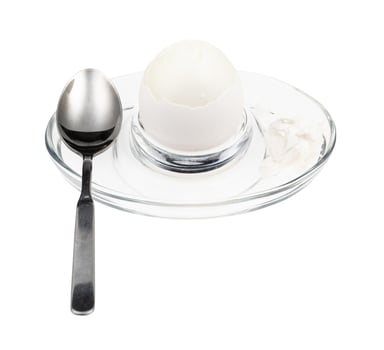 peeled boiled white egg and spoon in glass egg cup photo