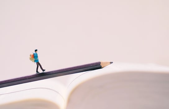 Miniature people figures with backpack walking on pencil and book with copy space, travel and study abroad concept photo