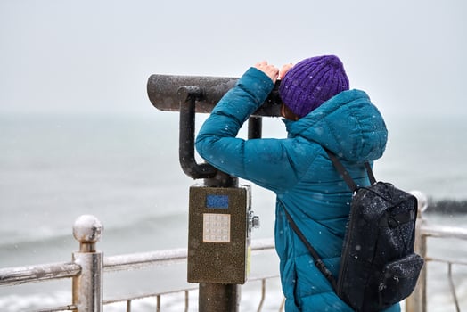 Woman looking through binocular viewer at sea in winter photo