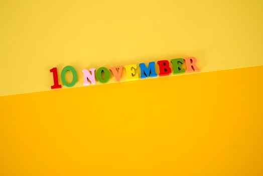 November 10 on a yellow, paper background with multicolored and wooden letters with space for text. photo