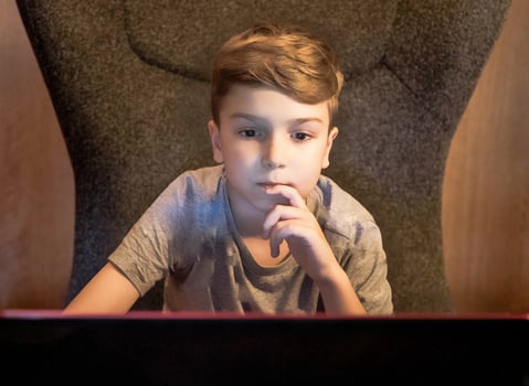 Cute kid using computer while e-learning at home. photo