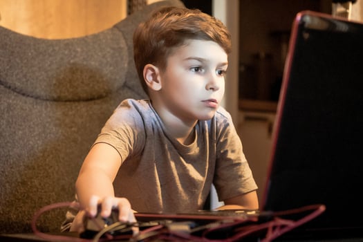 Little boy playing games on laptop at home. photo