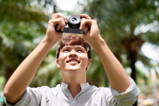 Young attractive man, a photographer, taking photographs in an urban area photo