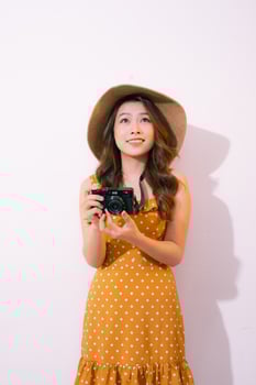 Stylish smiling woman posing with retro camera on pink background. photo