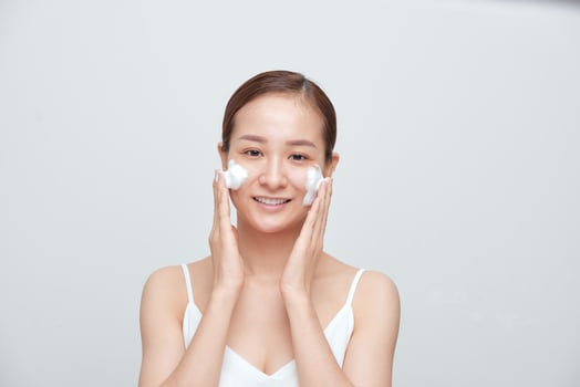 Cheerful Asian female woman applying foaming cleanser, has clean fresh healthy skin. photo