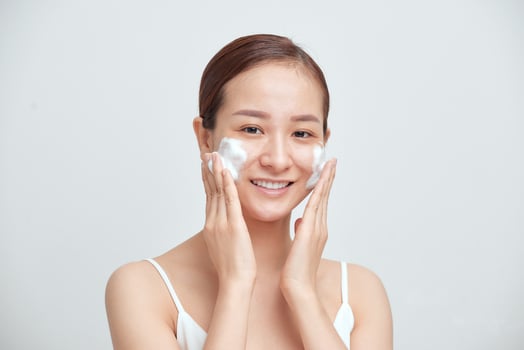 Cheerful Asian female woman applying foaming cleanser, has clean fresh healthy skin. photo