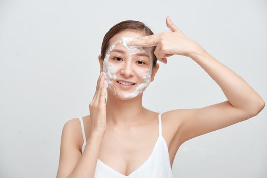 Portrait of cheerful laughing woman applying foam for washing on her face. photo