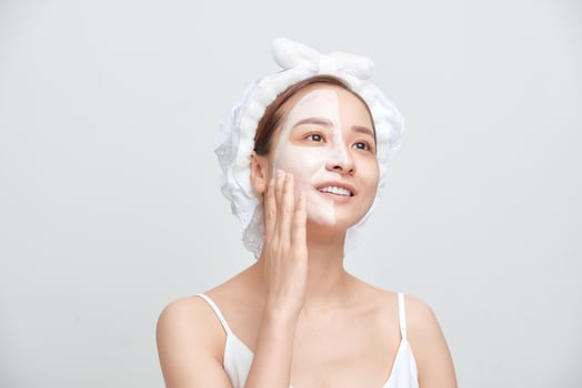 Portrait of young Asian woman applying facial clay mask photo
