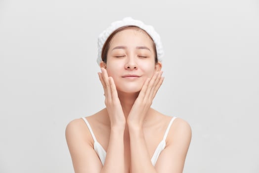Happy young girl with clean skin and with a white towel on her head washes face photo