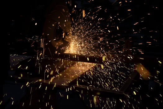 Lots of sparks from cutting metal in dark. Lights fly in different directions. Industrial background. photo