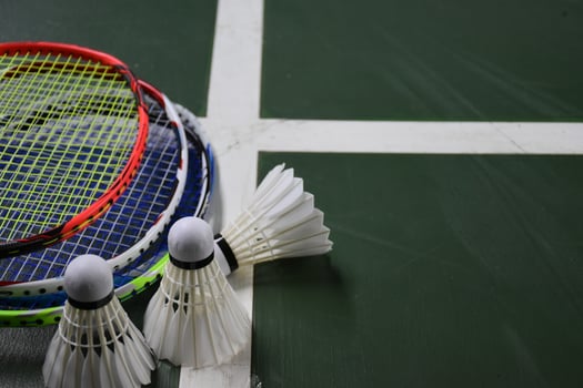Cream white badminton shuttlecocks and rackets on green floor in indoor badminton court photo