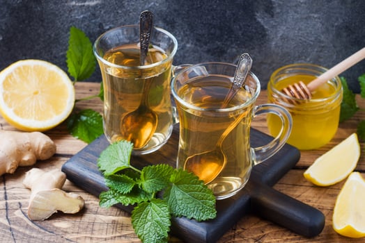 Two cups of natural herbal tea ginger lemon mint and honey on a wooden background. photo