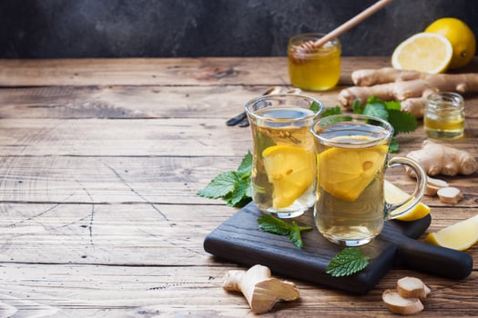 Two cups of natural herbal tea ginger lemon mint and honey on a wooden background. Copy space photo