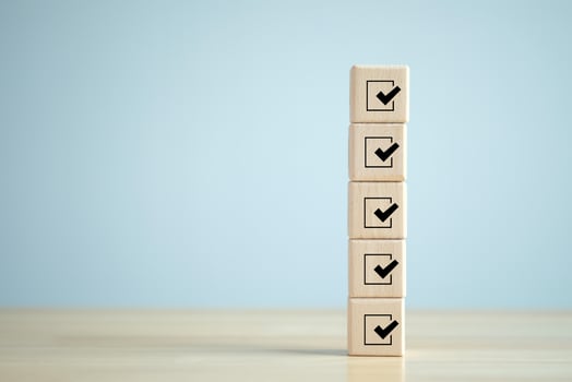 Checklist, Task list, Survey and assessment. Quality Control. Goals achievement and business success. Check mark icon on wooden blocks. photo