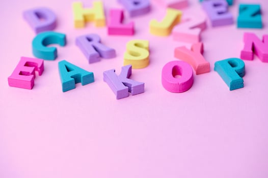 several colored wooden letters on pink background photo