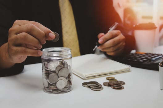 Man hand putting money coin and take note of income and expenses and working to save money for the future growing business, education and retirement. photo
