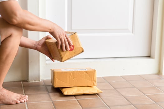 Woman collects parcel at door. box near door on floor. Online shopping, boxes delivered to your front door. Easy to steal when nobody is home. Parcel in cardboard box on doorstep. Delivery service photo