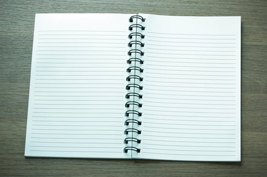 open spiral notebook on dark wood background photo