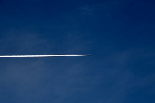 A plane flying in the blue sky and clouds. A white contrail from an airplane in the summer sky. photo