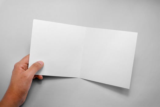 Hand holding square bifold brochure mockup photo