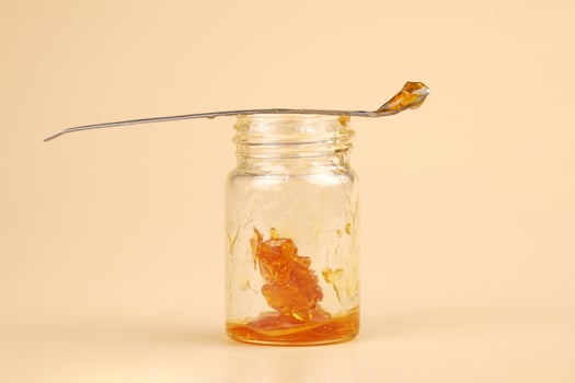 golden cannabis extract, marijuana bottle with resin and dabbing stick photo