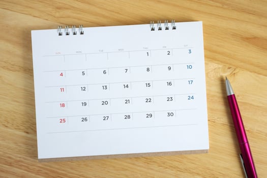 Calendar page with pen on wooden desk table photo