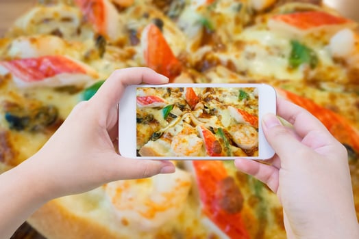 woman taking photo of Pizza and with mobile smartphone