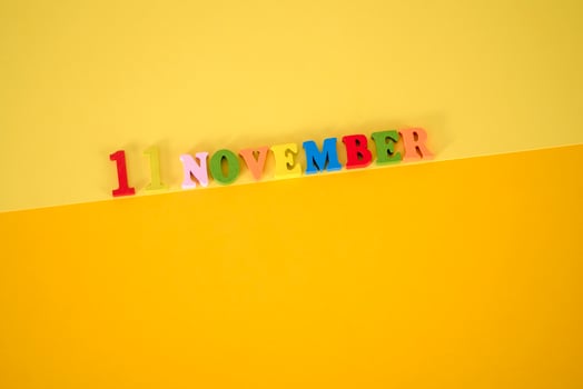 November 11 on a yellow, paper background with wooden and multicolored letters with space for text. photo