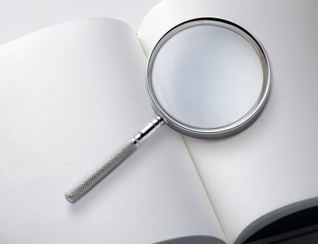 Open book closeup with turning pages and magnifying loupe. book in hard cover. Studying and research concept photo