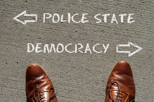 Top view on a man standing in front of the words Police State and Democracy with arrows pointing to the left and right side of the picture photo