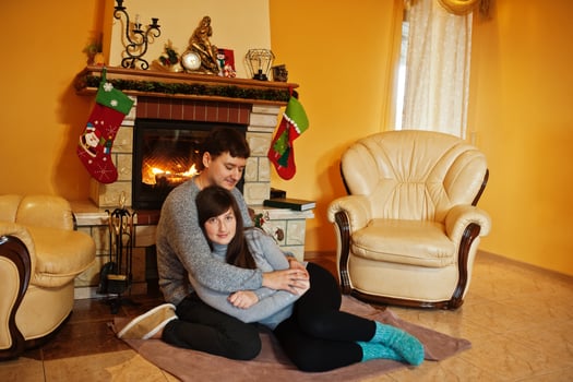 Happy young couple at home by a fireplace in warm living room on winter day. photo
