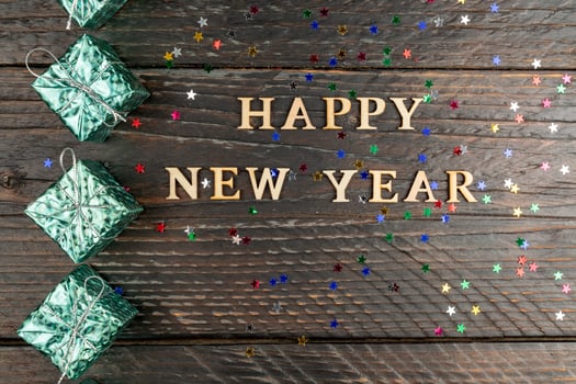 happy new year festive greeting card with sparkling confetti stars and blue smal gift boxes on wooden background photo