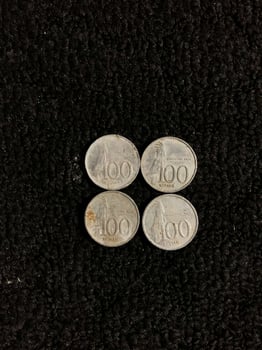 One hundred rupiah Indonesian coin with a picture of a parrot isolated on a dark background photo