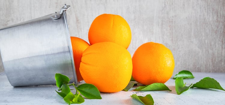 Fresh many oranges fruit in stainless steel basket and pour on the white wooden background. photo