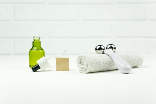 A CBD green oil, face roller, white cotton towel  lie on a white table photo