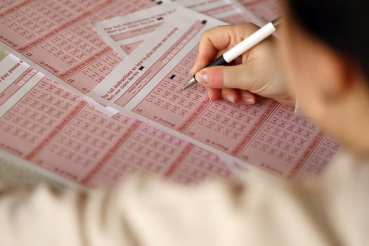 Filling out a lottery ticket. A young woman plays the lottery and dreams of winning the jackpot. Female hand marking number on red lottery ticket photo
