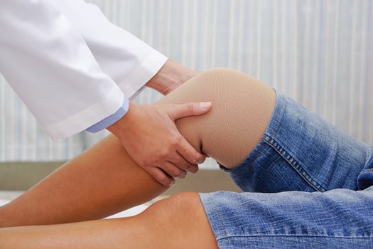 Doctor examining the knee of a patient with a bandage. Concept of Health check, health care and medical. photo
