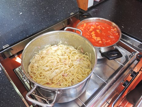 cooking pasta with sausage and meat gravy on stove photo
