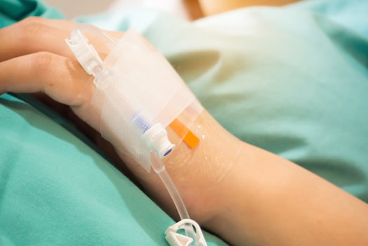 Asian woman patient hand on IV drip with saline solution, fluid replacement therapy photo