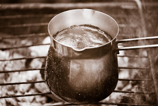 Natural, freshly roasted coffee is prepared in a metal Turk over a fire. Hot coffee with foam. photo