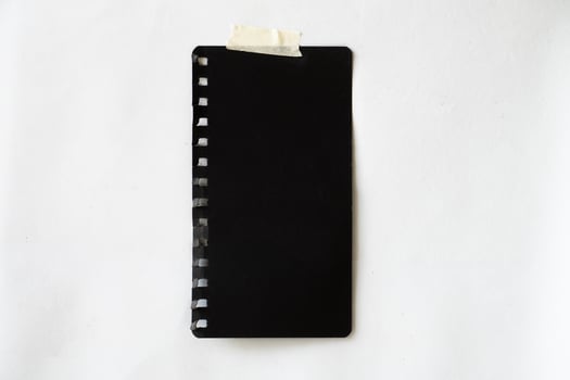 blank sticky note paper for mockup. black sketchbook glued with tape on the wall photo
