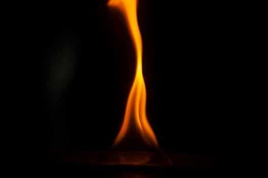 Flames in dark. One flame on black background. Ignition details. Fire burns yellow. photo